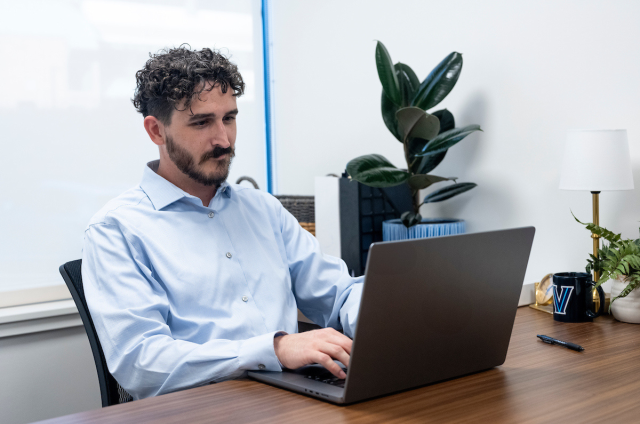 man at a desk typing on a laptop