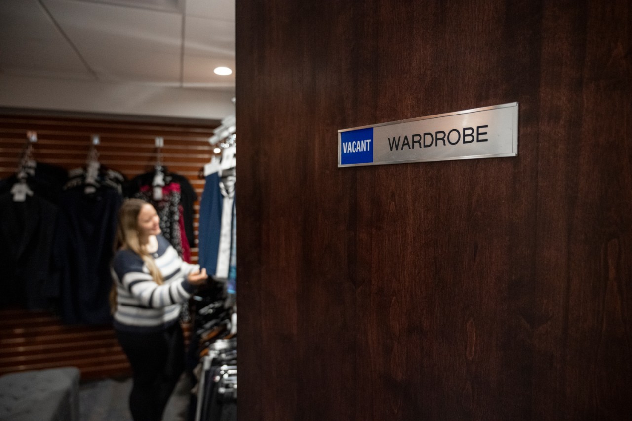 CSO692_20250415_2235 Student standing in the wardrobe looking at clothes with the door slightly open.