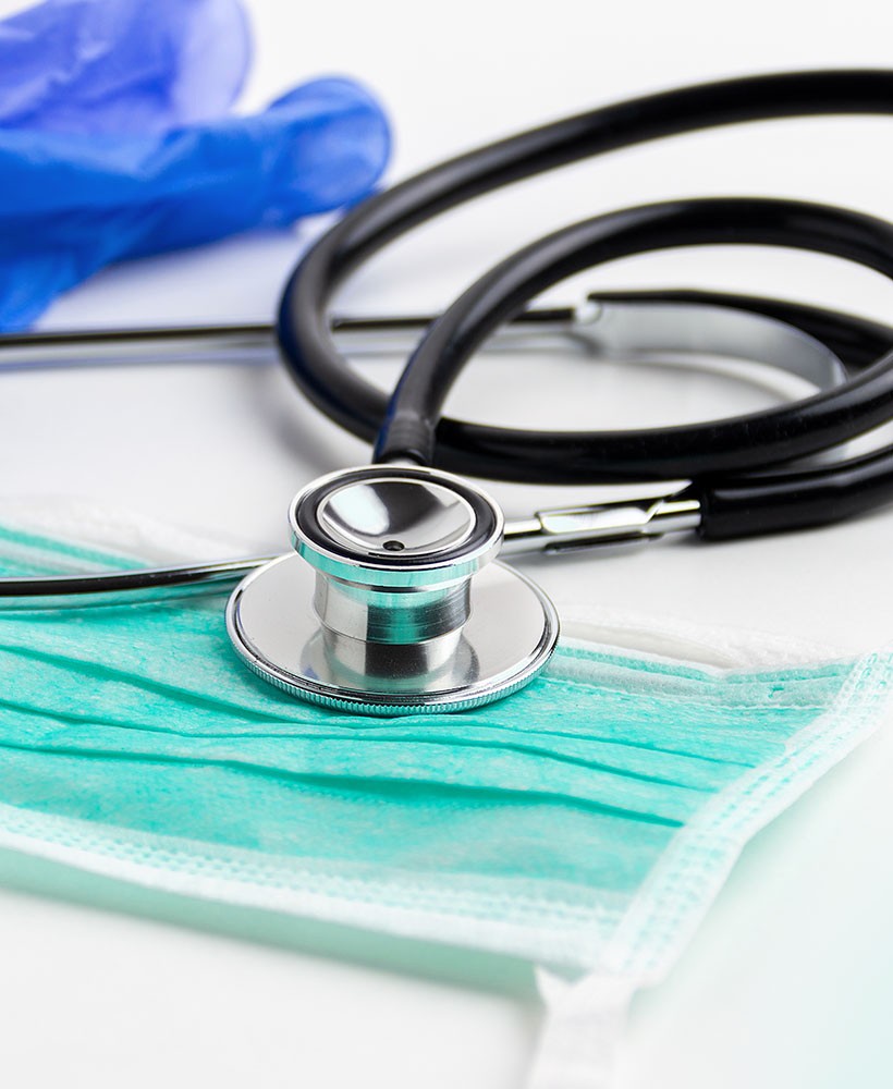 Stethescope on a table with a mask and gloves.