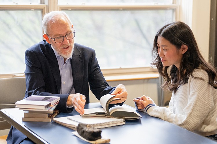 faculty member showing student key passages in a book