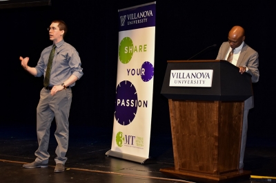 Villanova 3MT winner Samuel Sinemus presents on stage as Graduate Studies Dean Emory Woodard stands at the podium