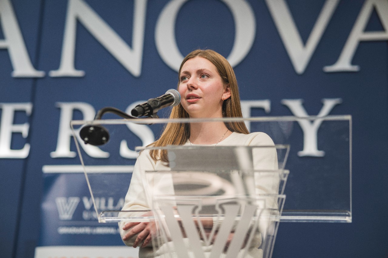 Graduate student presents on stage at the fall research symposium