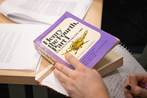 A student takes notes while reading "Henry the Fouth, Part 1"