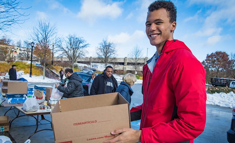 A student carries a box as he does volunteer work on campus. A student carries a box as he does volunteer work on campus.