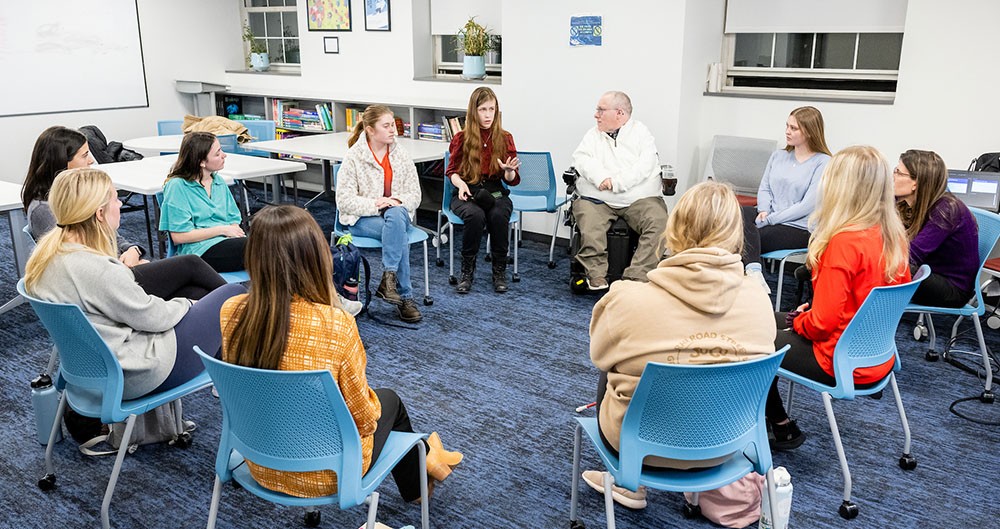 small focus group of people sitting in a circle in chairs in a classroom