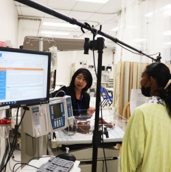 Sunny Hallowell crib c sm Dr. Sunny Hallowell in simulation lab with actress and neonatal ICU equipment and infant manikin