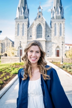 Hailey Clark 21 BSN church Hailey Clark in graduation gown in front of campus church