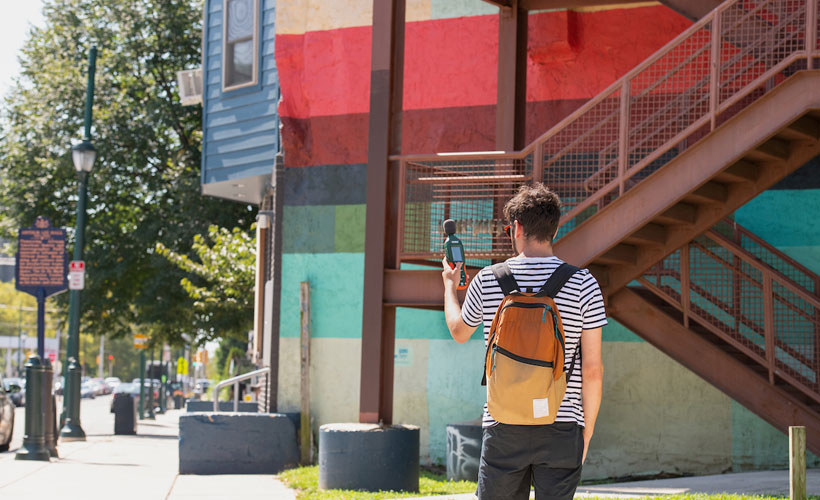 Male student performing air monitoring research outside