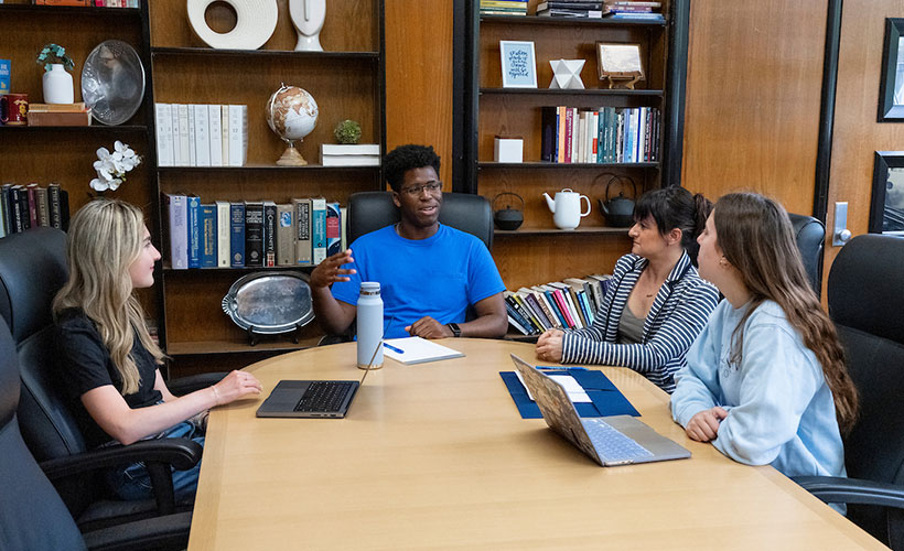 Students and professor sitting at table