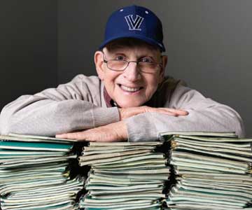 Professor Gerald A. Dougherty standing in front of magazines