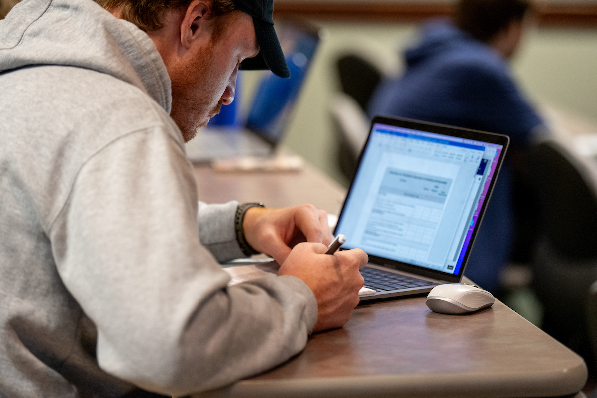 student working on a laptop in a classroom setting