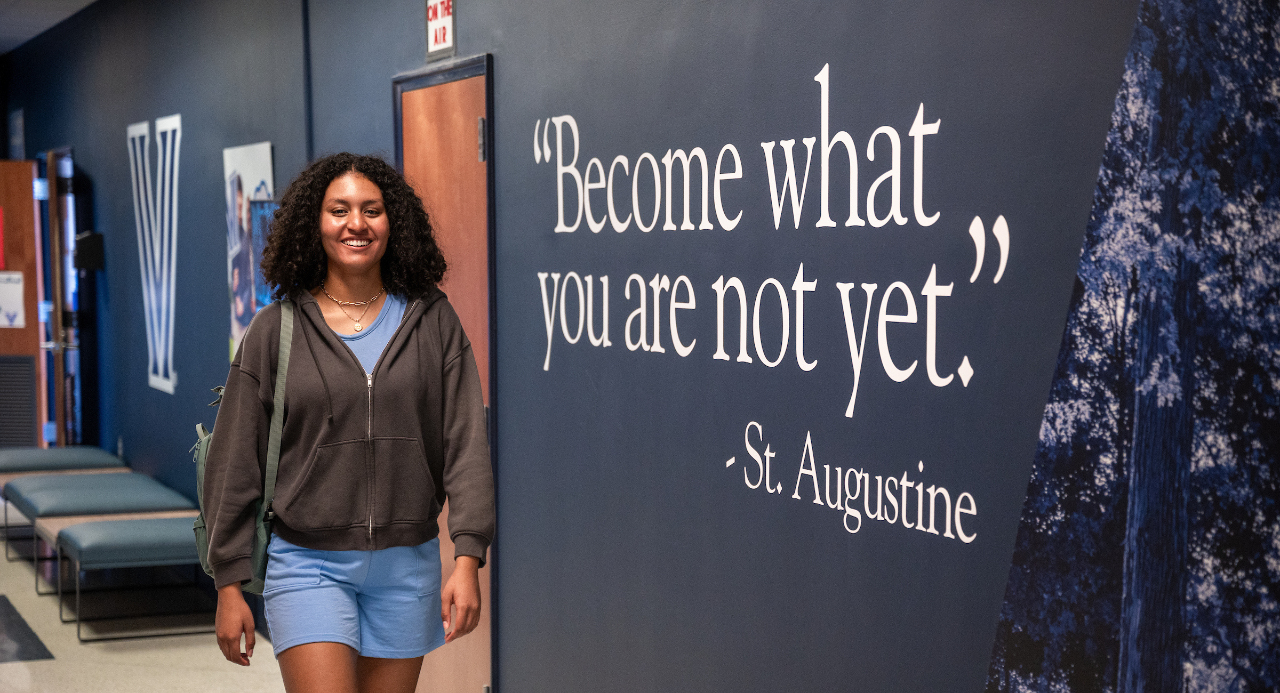 Student standing next to "become what you are not yet" quote