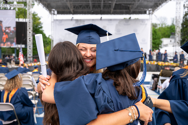 Group of alumni hugging at commencement