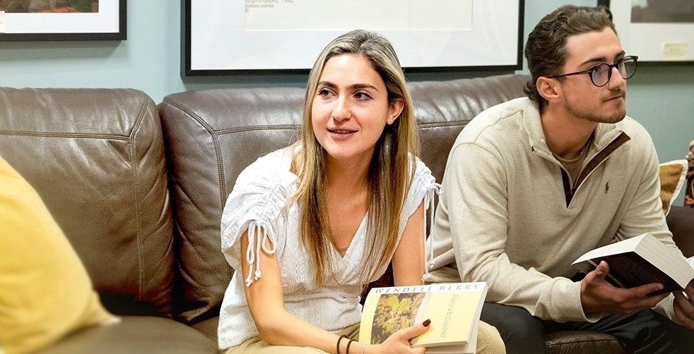 Three Villanova students sit comfortably in the Humanities lounge holding great books.