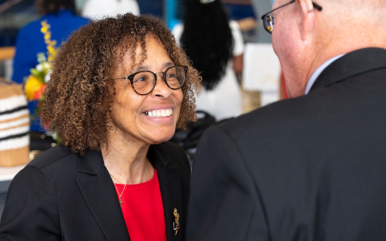 A smiling Teresa Nance speaks with a male gueA smiling Teresa Nance speaks with a male guest at her retirement celebration.st at her retirement celebration.