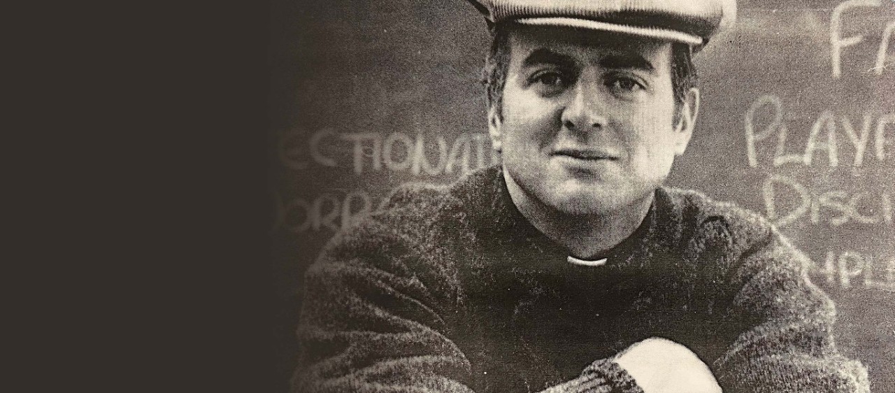 portrait of the Rev. John P. Stack dressed casually in a classroom